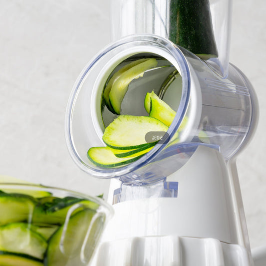 vegetable cutter processes cucumber into shredded pieces, in a small glass bowl below its respective slicer.